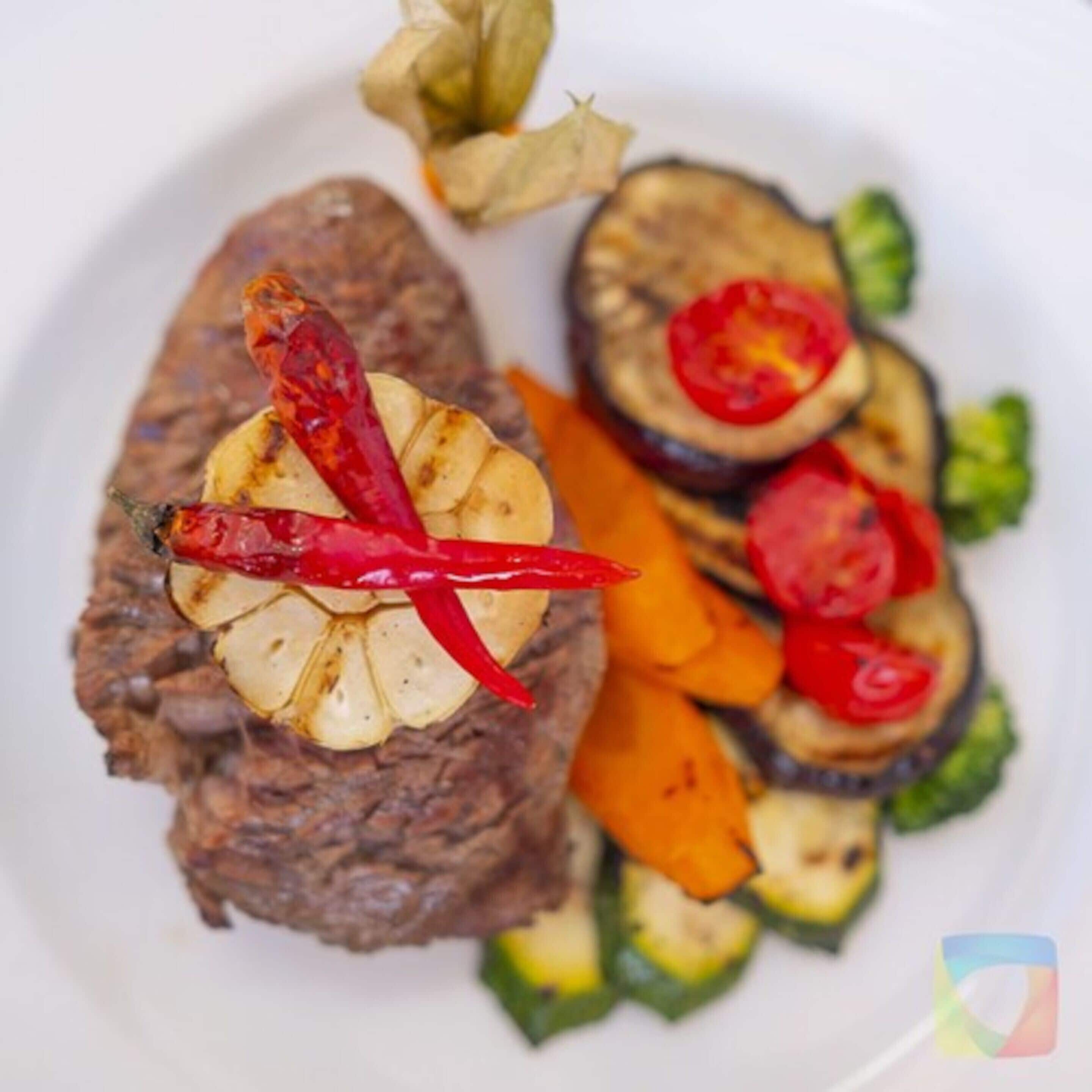 A plate with grilled meat, sliced zucchini, and cherry tomatoes.