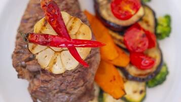 A plate with grilled meat, sliced zucchini, and cherry tomatoes.