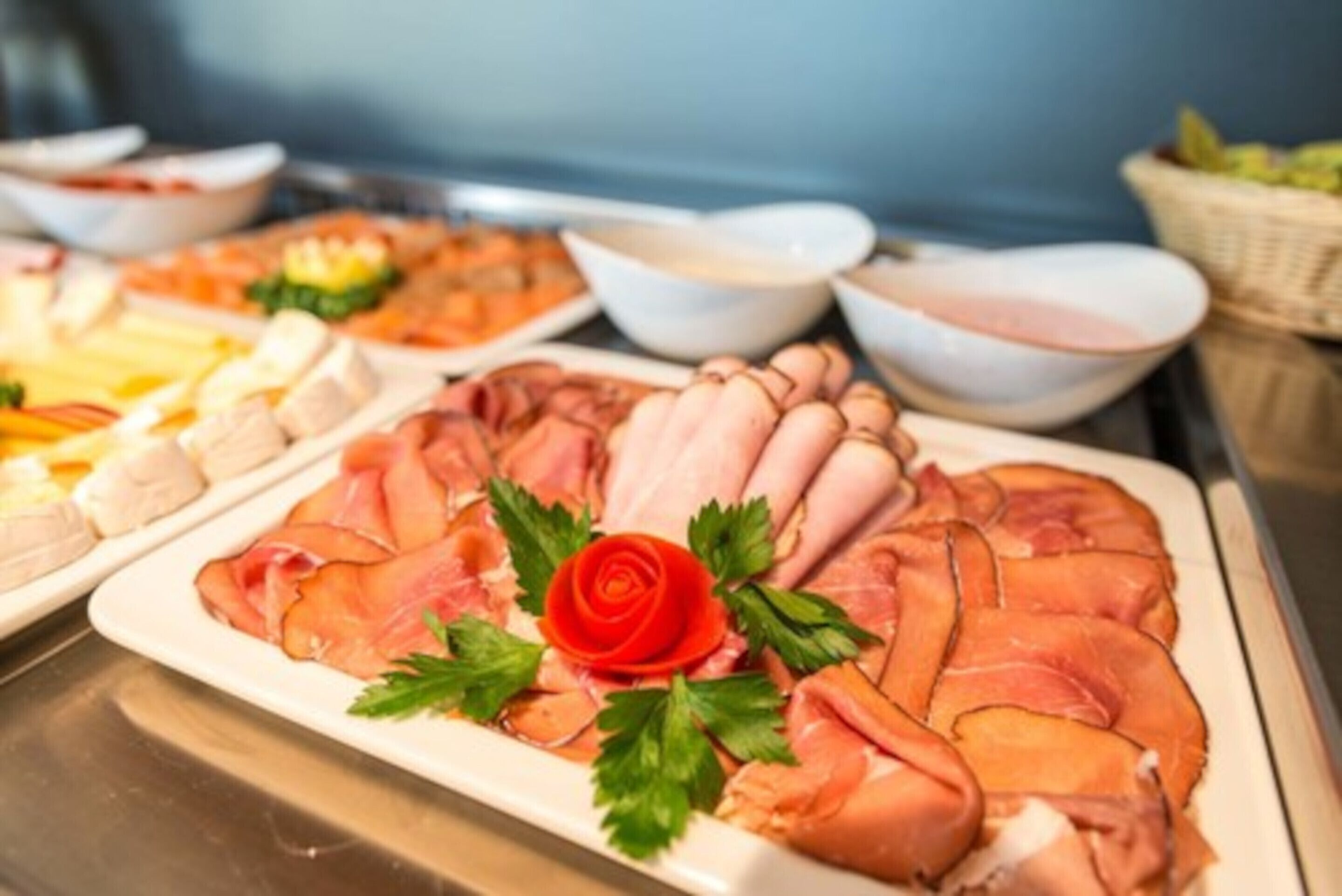 Buffet com diversos tipos de carne e acompanhamentos, incluindo um arranjo de rosas como peça central.