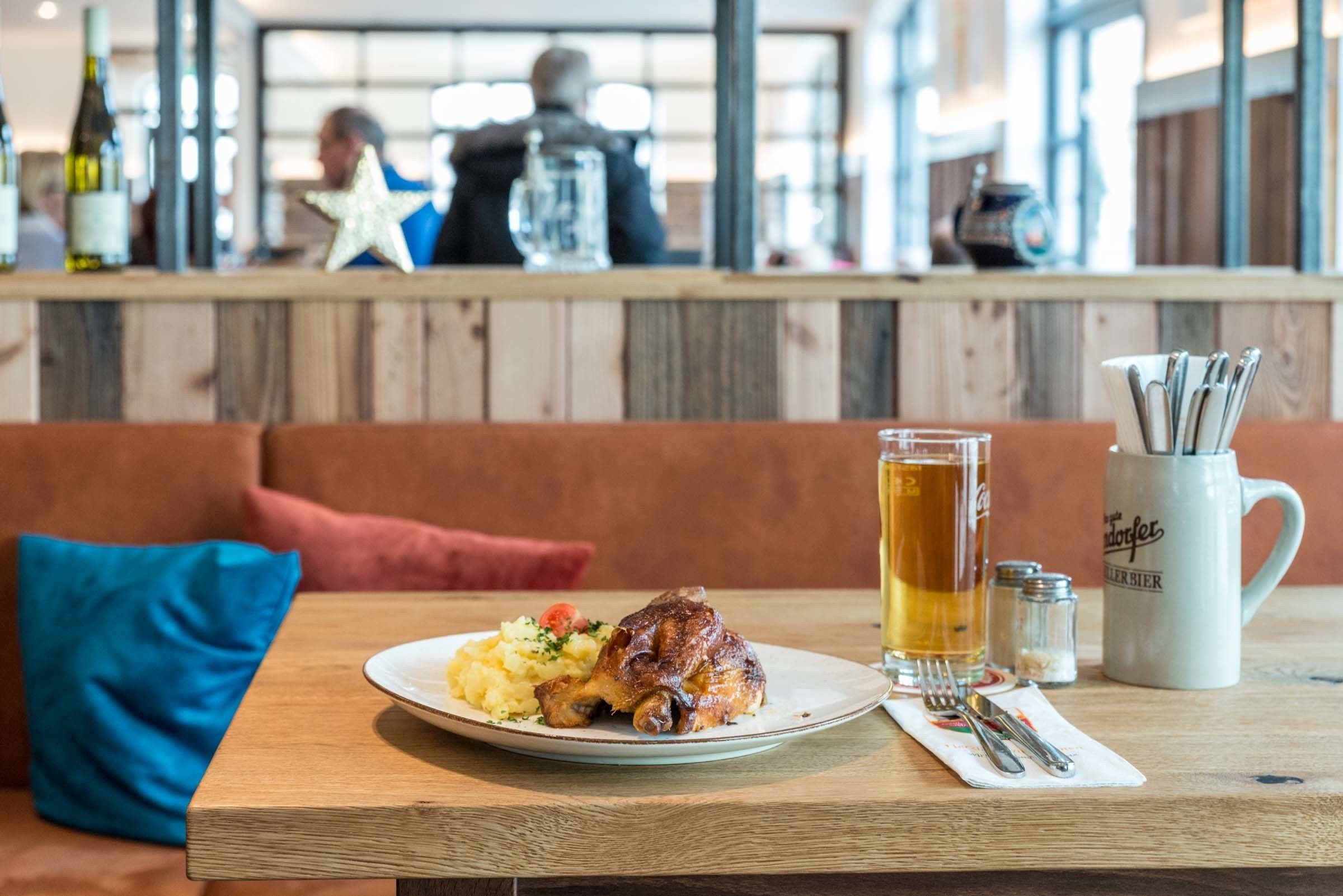 A dining table with a plate of food, a glass of beer, and a mug.