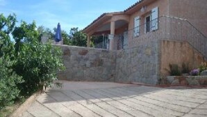 A building with a stone facade, a covered porch, and a paved area in front. - houses / villas - 3 rooms - 4/5 persons (Zonza)