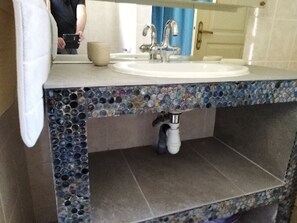 Ein Badezimmer mit Waschbecken, Spiegel und dekorativer Mosaikfliesenbordüre.