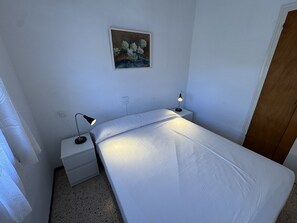 Une petite chambre à coucher, bien rangée, avec un lit simple, des tables de chevet et un tableau accroché au mur.