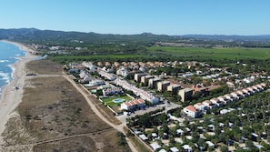 Luftaufnahme eines Küstenresorts mit Villaanlagen, einem Strand und einer Bergkulisse.