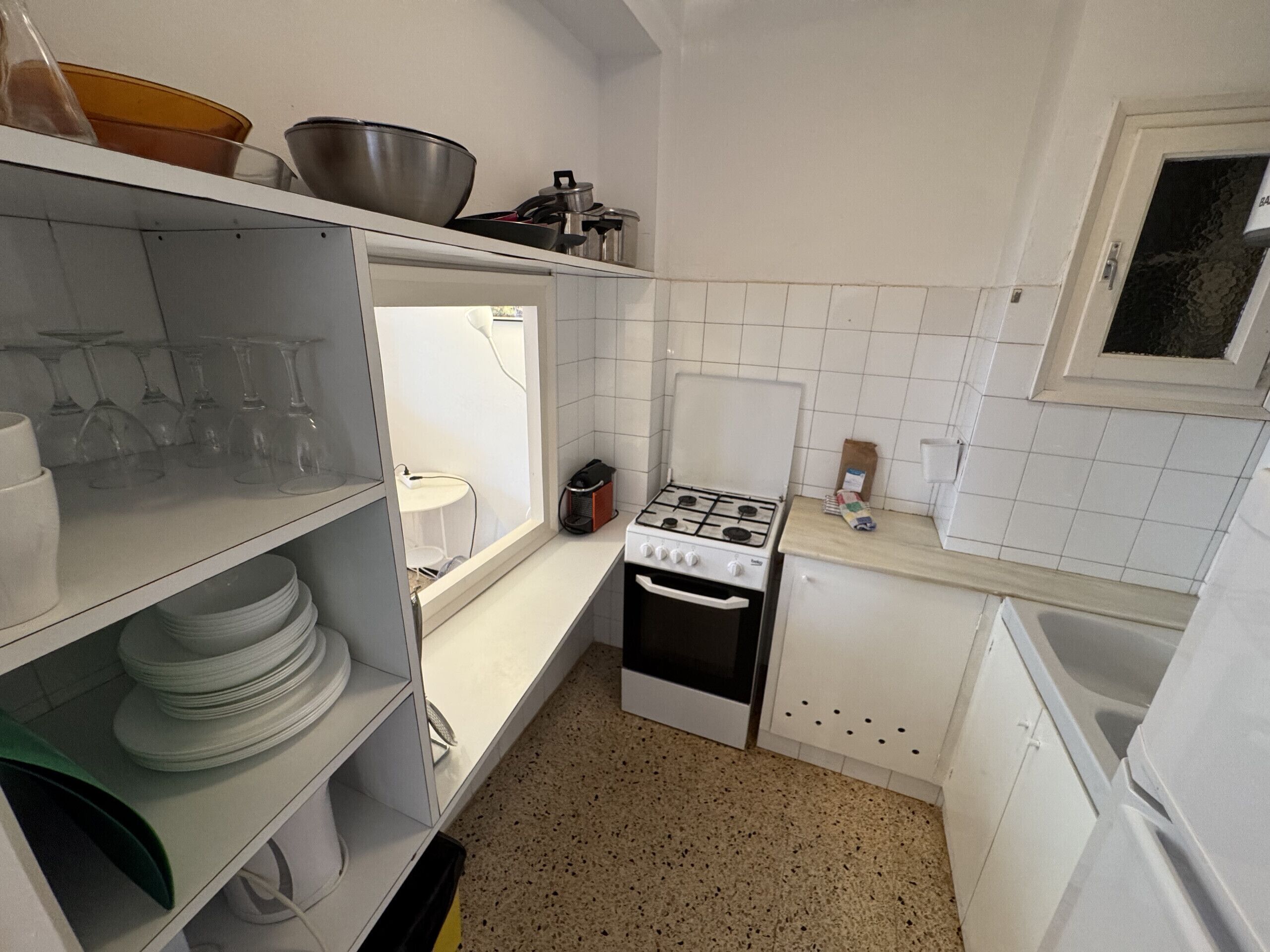 A compact kitchen with white cabinets, a stove, and a sink.