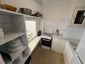 A compact kitchen with white cabinets, a stove, and a sink.