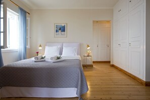 A bedroom with a large bed, a bedside table with a lamp, and a wardrobe. - Sea Breeze Villa with stunning views in Corfu with private path to the beach (Nisaki)