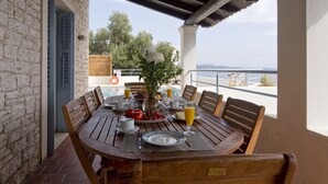 Une table en bois, dressée pour le petit-déjeuner, avec vue sur la mer.