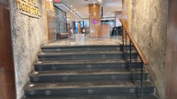 A hotel entrance with a staircase leading to the lobby, featuring a 'Tiger Trail' sign and 'PUSH' instructions on the floor. - Regenta Place Bangalore, Cunningham Road (Bengaluru)