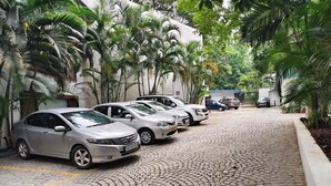 A cobblestone driveway with parked cars and lush greenery. - Regenta Place Bangalore, Cunningham Road (Bengaluru)