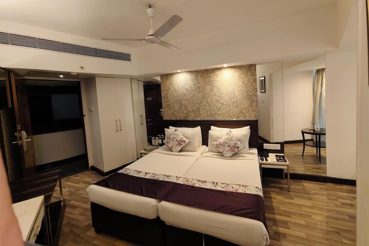 Una habitación de hotel moderna con una cama grande, un ventilador de techo, una mesita y un escritorio.