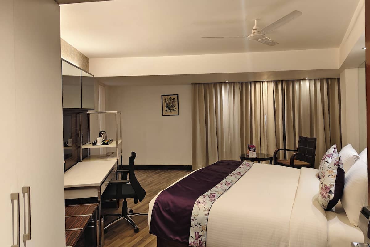 Una habitación de hotel con cama, escritorio, silla y ventilador de techo.