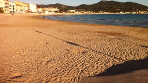 Ein Strand mit Gebäuden im Hintergrund und einem Berg in der Ferne.