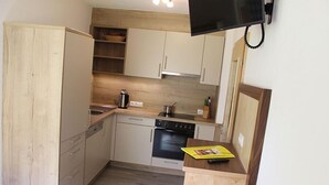 Une cuisine de taille réduite, avec des meubles de rangement en bois, une cuisinière et un petit plan de travail.