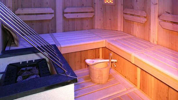 Un sauna en bois, avec des bancs, une lucarne et un seau.