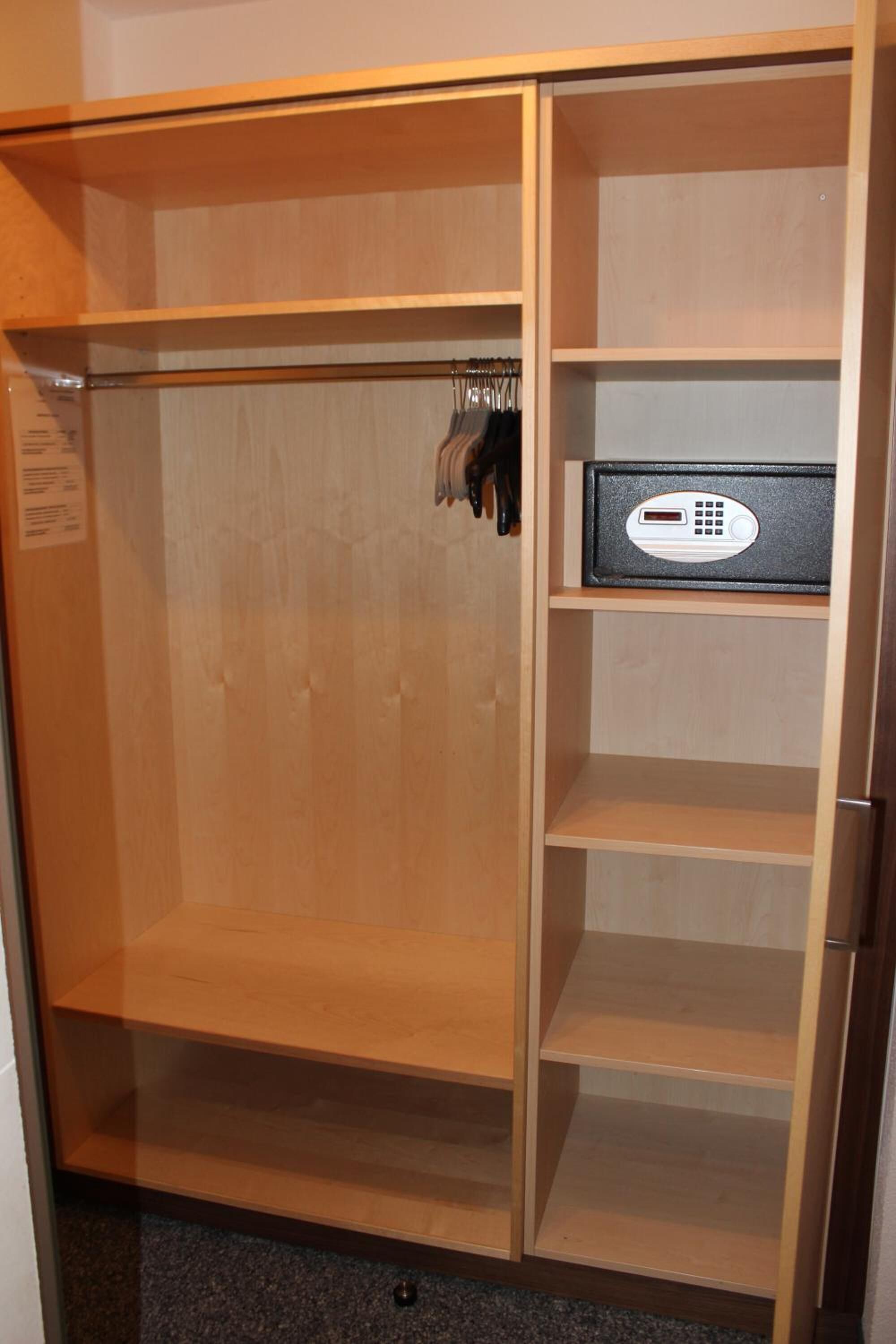 A wooden wardrobe with a mirror and a safe.