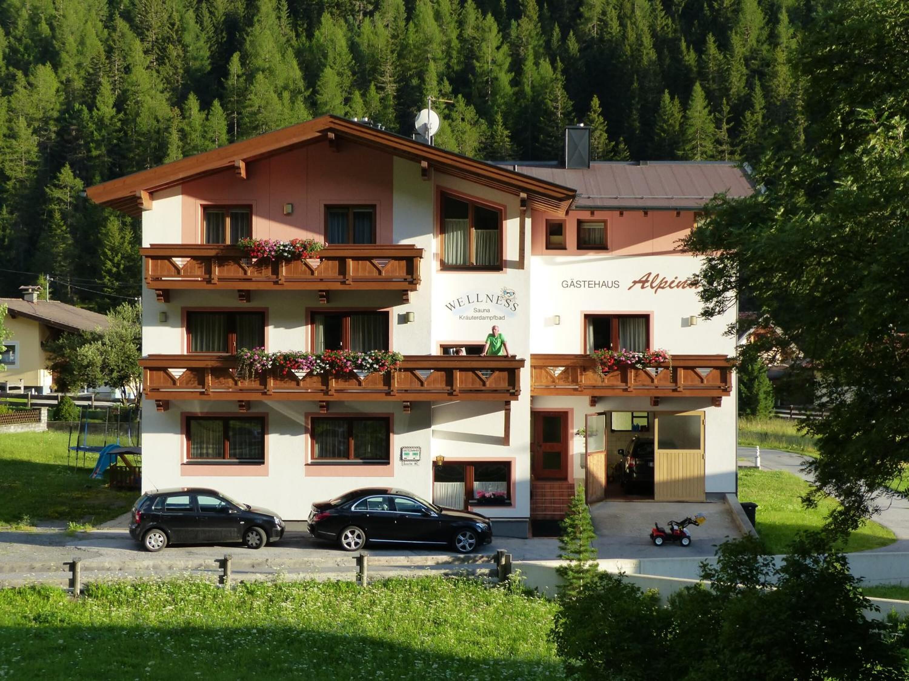 Un hotel de varios pisos con balcones decorados con flores, una sauna y un restaurante.