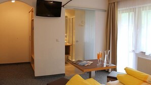 Une chambre d’hôtel avec un lit, une table avec des boissons, une télévision et une salle de bain visible à travers une porte ouverte.