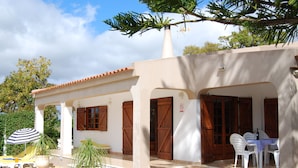 A covered outdoor seating area with a table and chairs, a striped umbrella, and potted plants. - Modern Villa in a quiet spot, with a large private  swimming pool (Espiche  Luz Lagos)