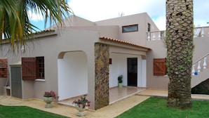 A modern house with a stone pillar, a wooden door, and a small garden area with a palm tree. - Modern Villa in a quiet spot, with a large private  swimming pool (Espiche  Luz Lagos)