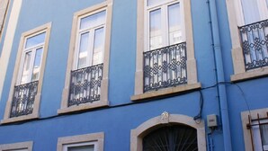 A multi-story building with a blue facade, multiple windows with white frames, and balconies with wrought iron railings. - Cozy Apartment in Anjos | Maria da Fonte | Terrace (Lisboa)