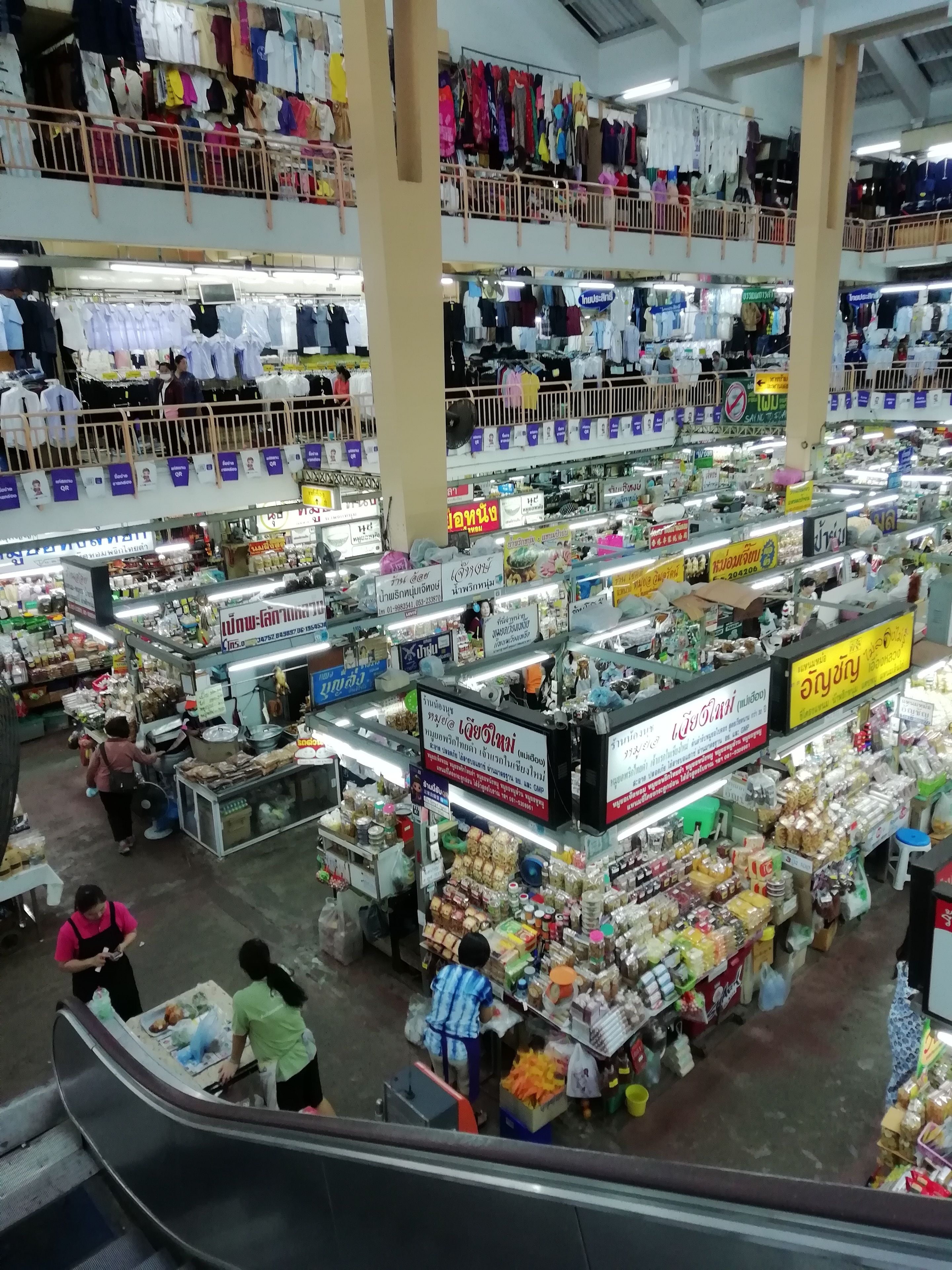 Un mercado techado de varios niveles con puestos que ofrecen comida, bebidas y artículos para el hogar.