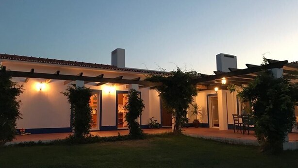 Una casa de dos pisos con un porche cubierto, un garaje a la vista y un césped bien cuidado.