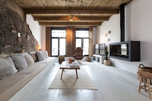 A cozy living room with a wooden ceiling, a sofa, a coffee table, and a fireplace.