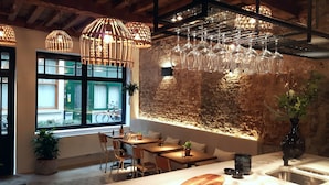Um restaurante com parede de tijolos rústicos, mesas de madeira e copos de vinho pendurados.