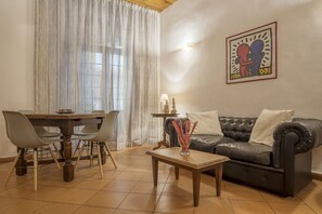 Un salon comprenant une table à manger, des chaises, un canapé, une table basse et une œuvre d’art accrochée au mur.
