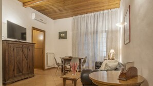 Una sala de estar con televisión, aparador de madera, mesa de comedor y sofá.
