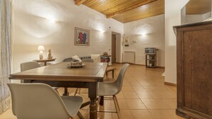 Un comedor con una mesa y sillas de madera, una cocina al fondo y un techo de madera.