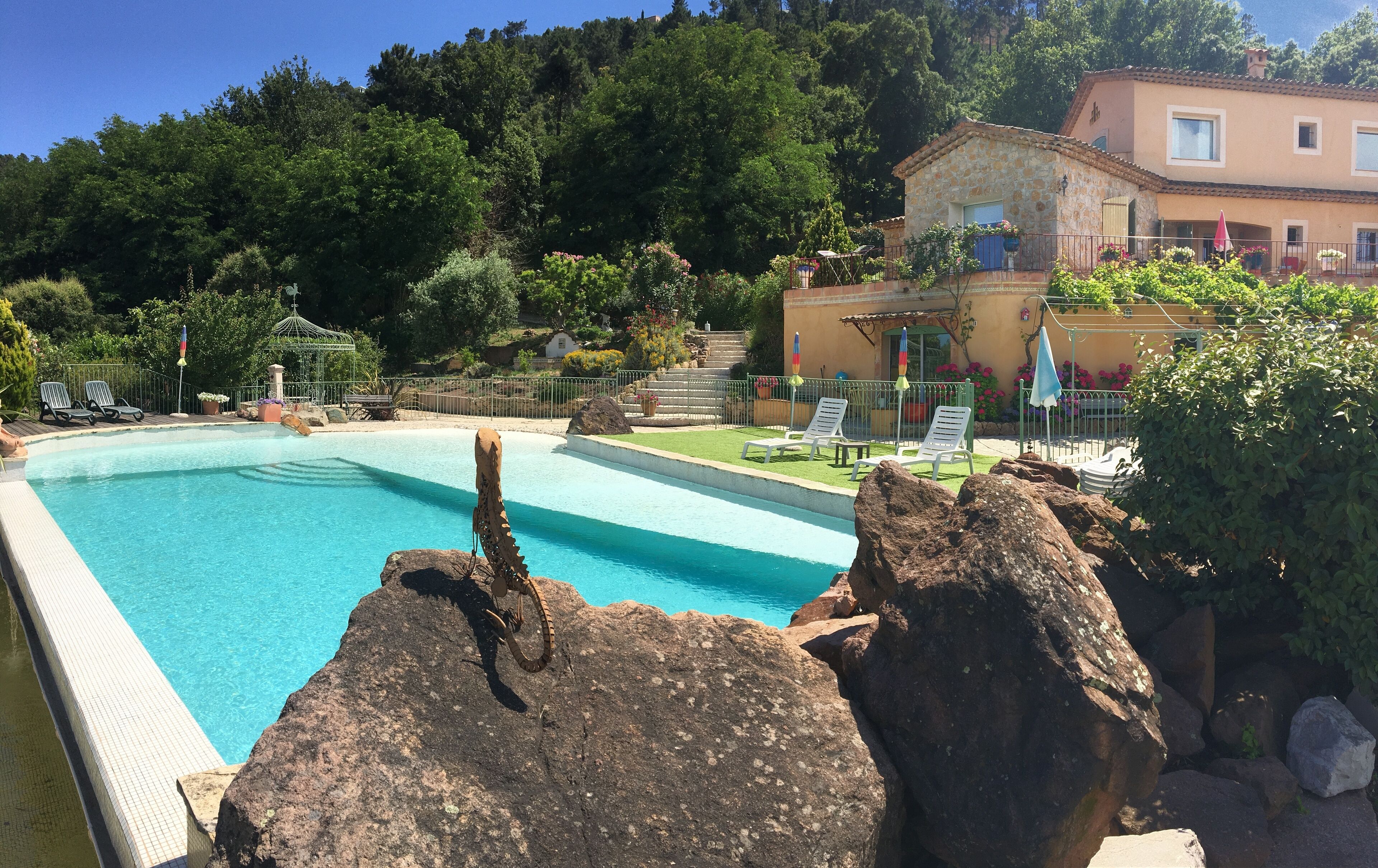 A swimming pool with a rock feature, surrounded by lounge chairs and a garden.