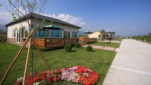 A modern residential area with a house featuring a deck, a well-maintained lawn, and a concrete pathway. - Countryside B&B (Ruisui)