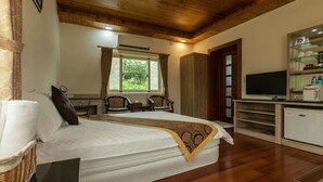 A bedroom with a large bed, wooden ceiling, a television, and a small kitchenette. - Countryside B&B (Ruisui)