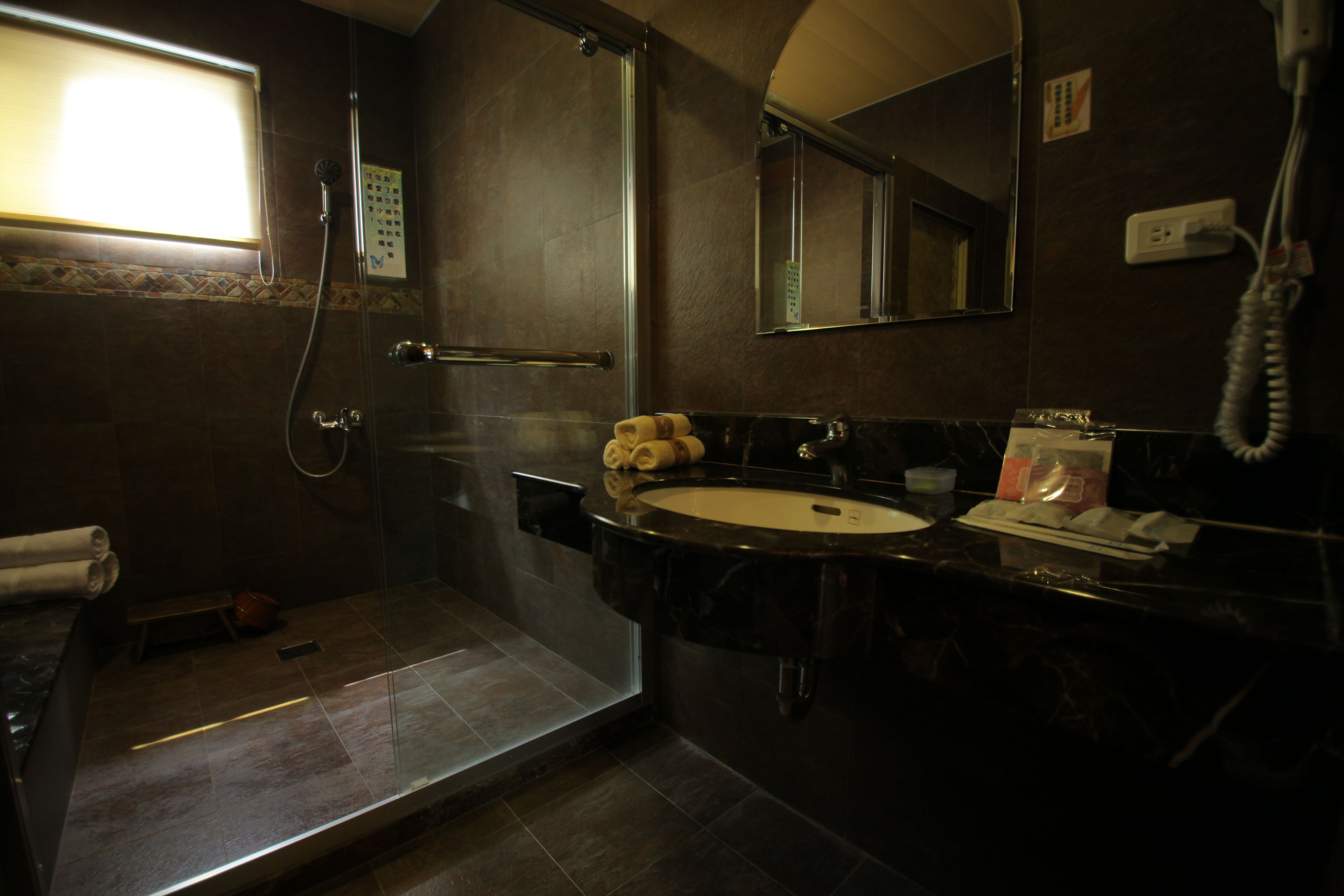 A bathroom with a glass-enclosed shower, a sink, and a mirror.