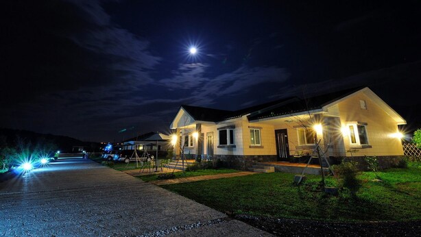 A two-story house with a well-lit driveway and a visible front porch. - Countryside B&B (Ruisui)