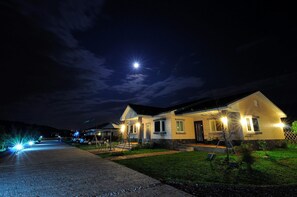 A two-story house with a well-lit driveway and a visible front porch.