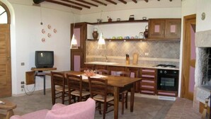 A compact kitchen with wooden cabinets, a dining table, and a fireplace.