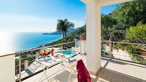 A balcony with a pool, dining table, and chairs, overlooking a coastal view with a clear sky. - Pool villa with sea view near Taormina, Sicily (Taormina)