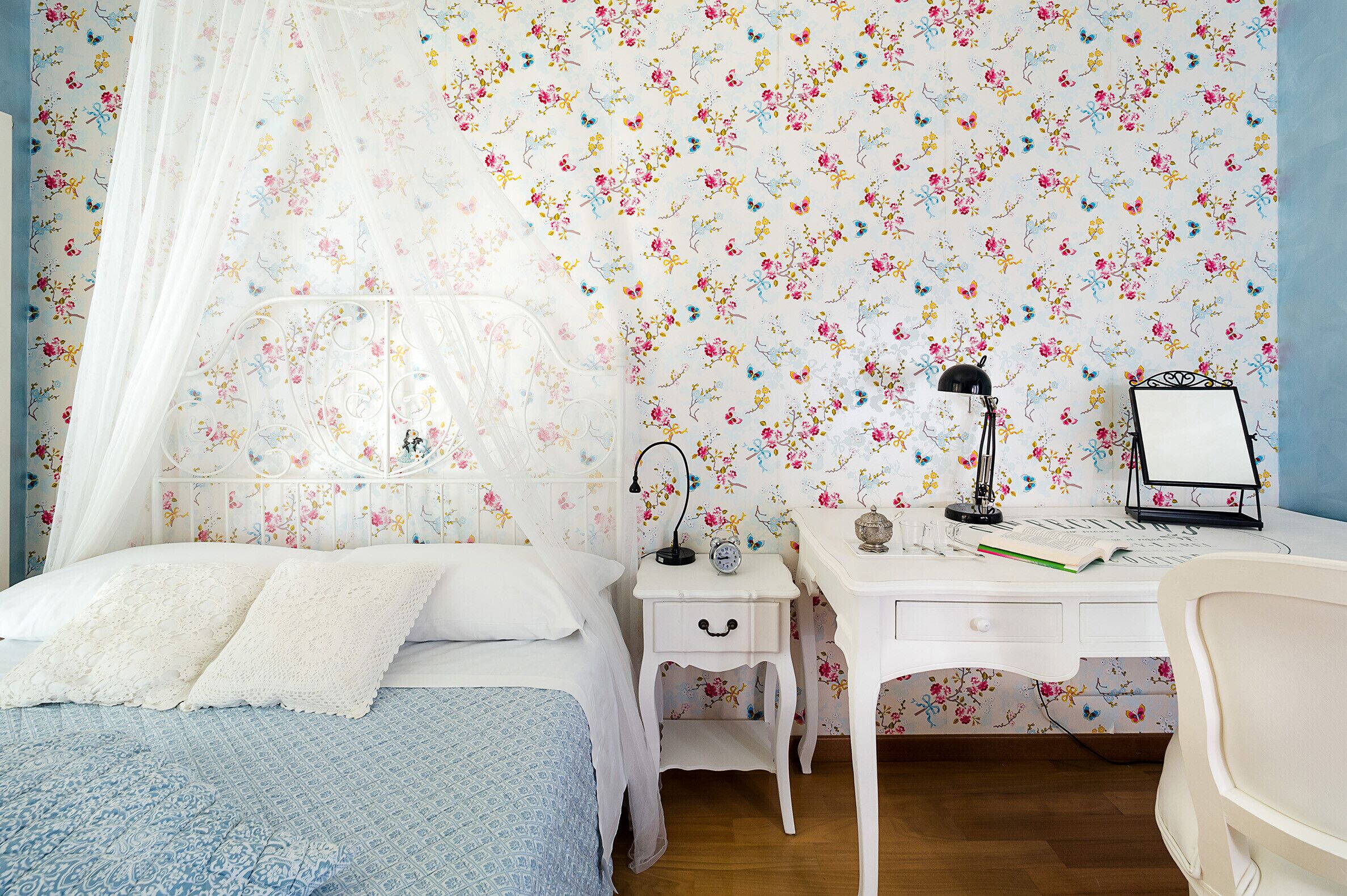 Un dormitorio con cama, mesita de noche, escritorio y silla.