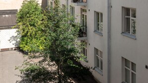 A multi-story building with balconies, a tree in the courtyard, and a clear sky. -  2ndhomes Beautiful & Modern 1BR Home with Central Location (Helsinki)