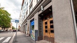 A street view with a building featuring a wooden door and a blue sign. -  2ndhomes Beautiful & Modern 1BR Home with Central Location (Helsinki)