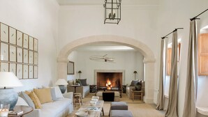 A spacious living room with a fireplace, a sofa, a coffee table, and a dining area. - Finca Serena Mallorca, Small Luxury Hotels (Montuiri)