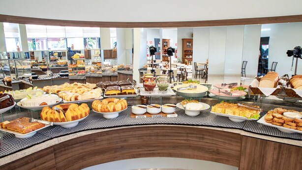 A buffet with various food items and a seating area with chairs and tables. - Hotel Jardim (Jardim)