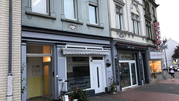 Un edificio con un escaparate que dice "A&S Immobilien" y otro con "FROHSINN".