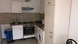 Una cocina compacta con estufa, horno, lavadora y refrigerador.