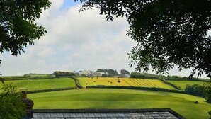 A view of a green field with a building in the distance. - Barley Cottage (Bideford)