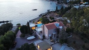 En ejendom ved kysten med swimmingpool, båd og havudsigt.