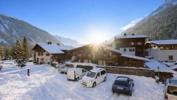 Un village de montagne enneigé, avec des bâtiments en bois et des voitures garées.